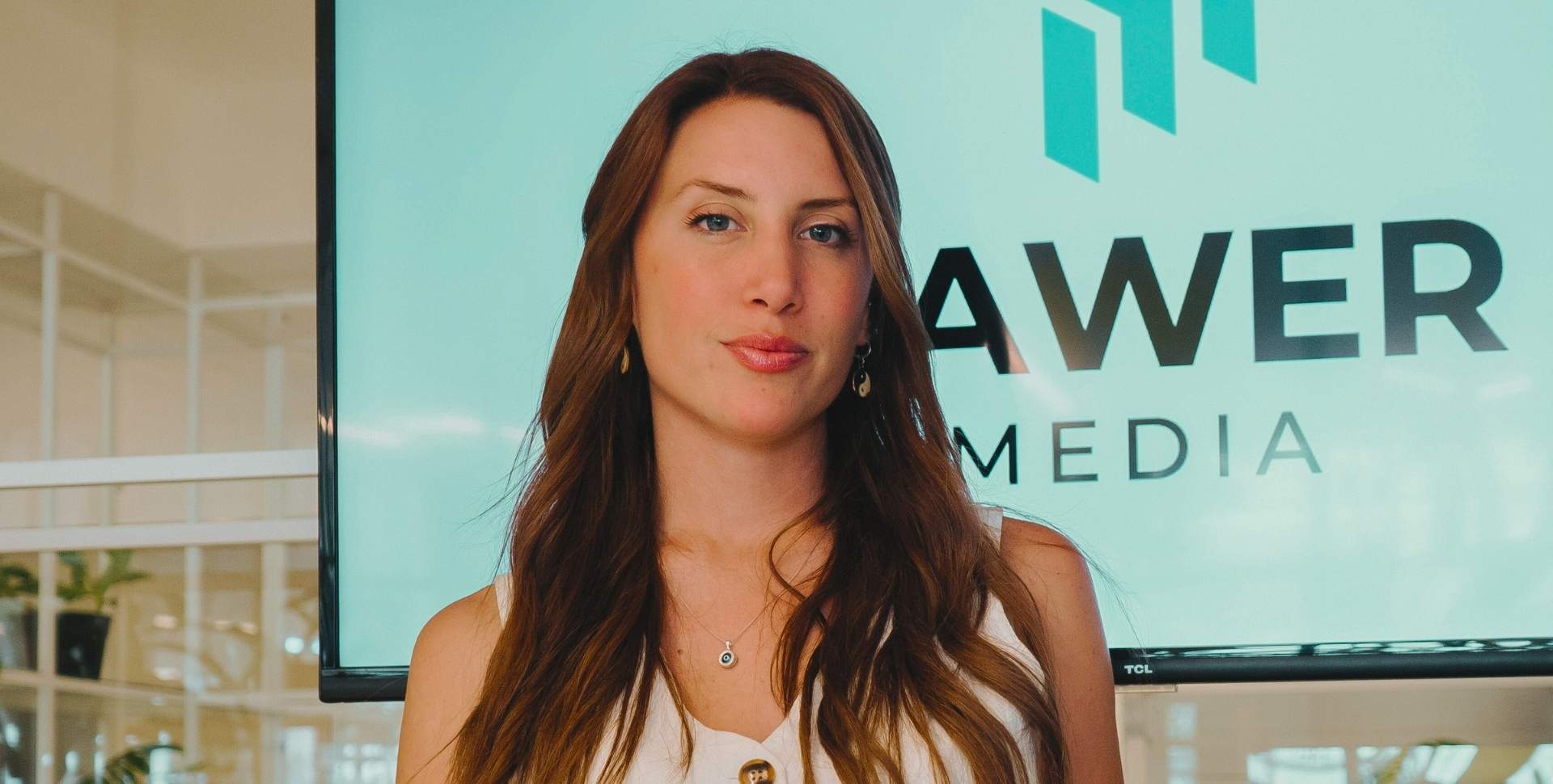 Estratega de Pawer Media frente al logo de la agencia, especialistas en marketing de resultados para e-commerce.